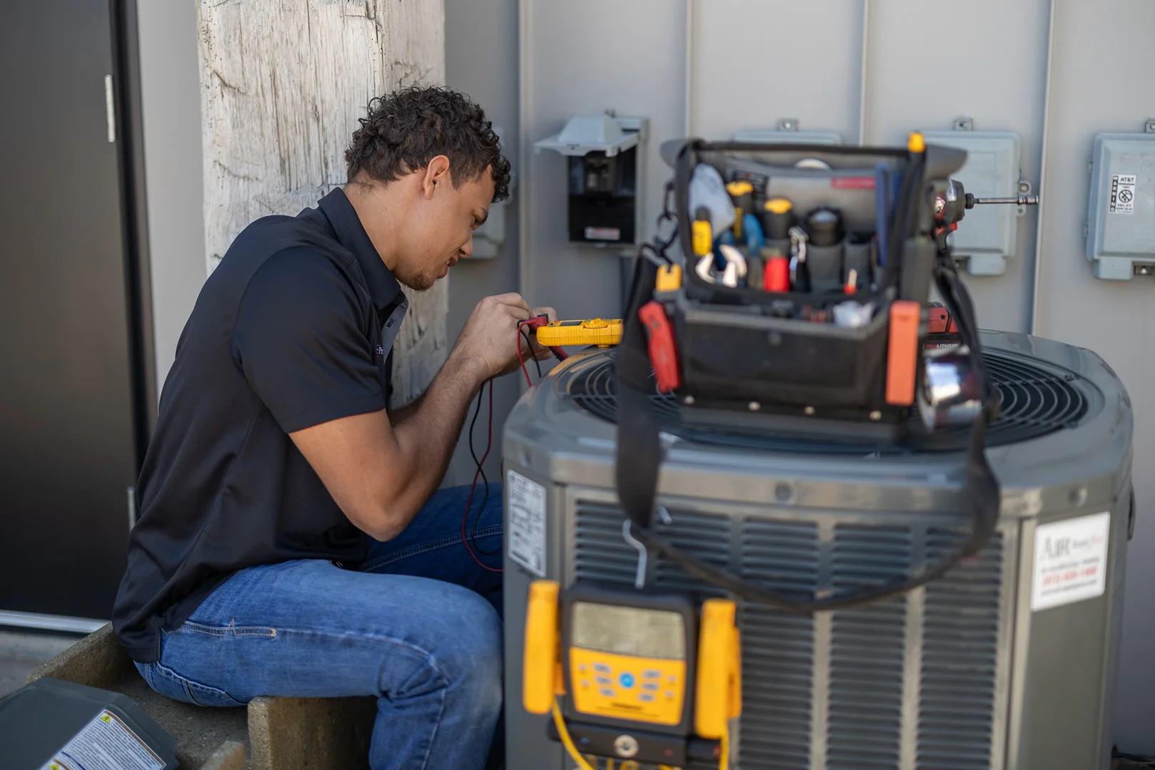 HVAC technician inspecting an outdoor condenser during a professional AC tune-up