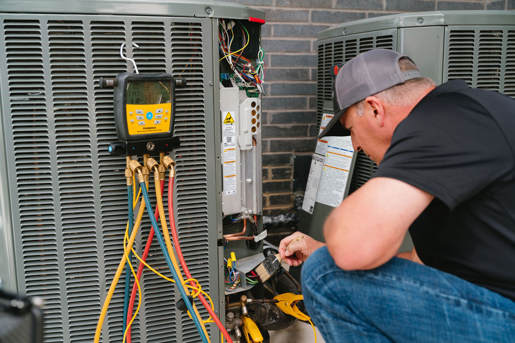 HVAC technician reviewing an AC tune-up checklist beside a residential condenser in McKinney, TX